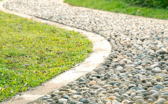 Curved path with small stones bordered by grass.